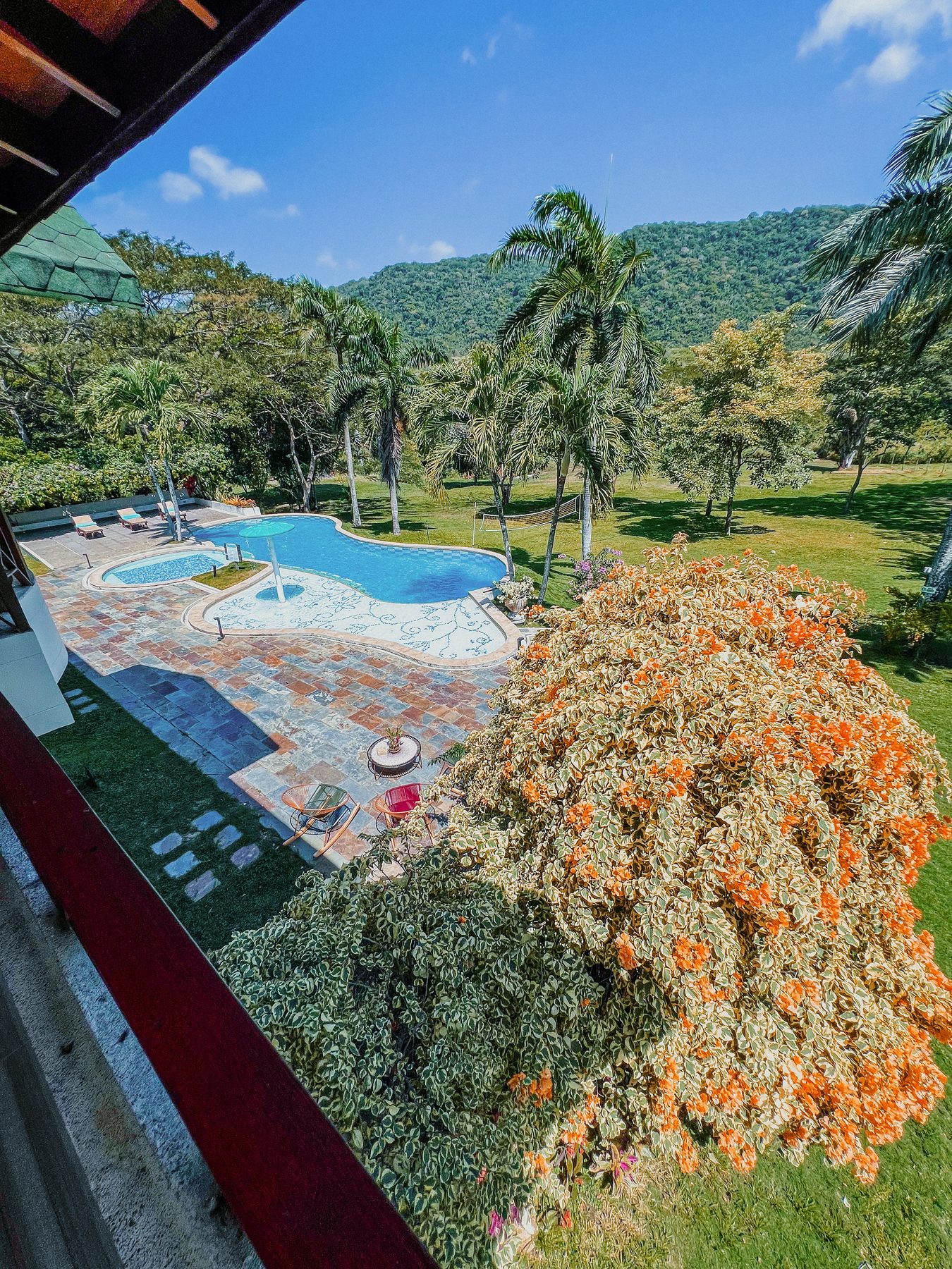 The lagoon pool framed by bougainvillea, seen from the upper veranda